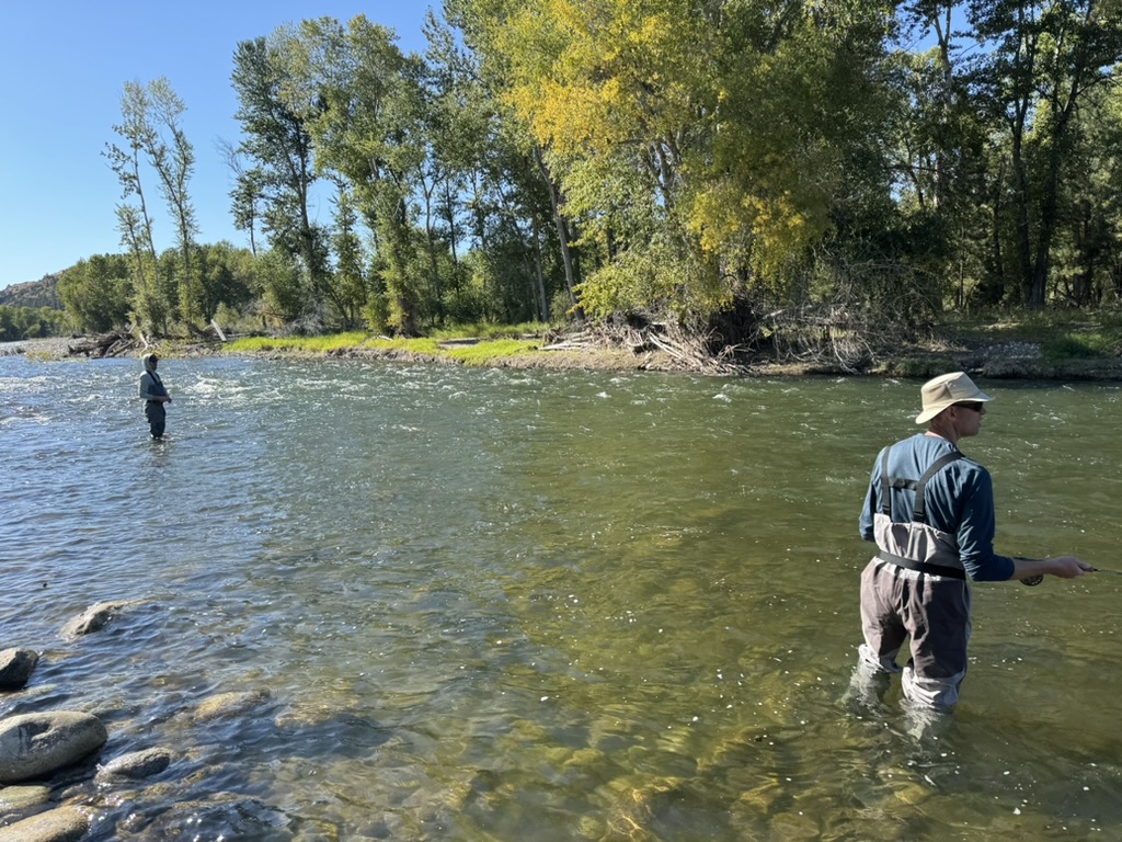 Two anglers wade fishing on a fall afternoon