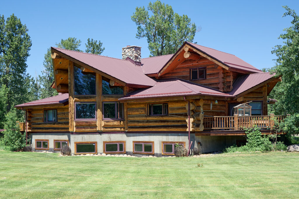 The lodge's log exterior and railed deck, viewed across the lawn with the great-room windows in view